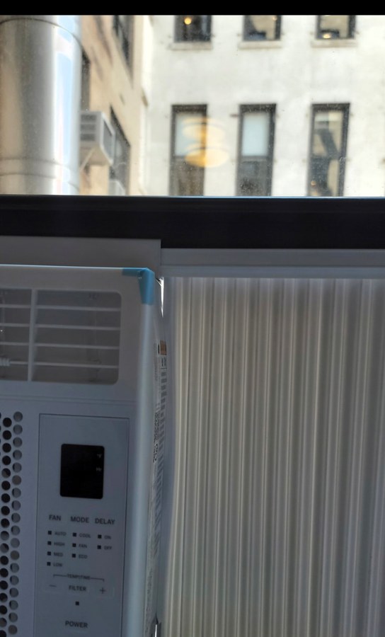Accordion side panel beside a window AC